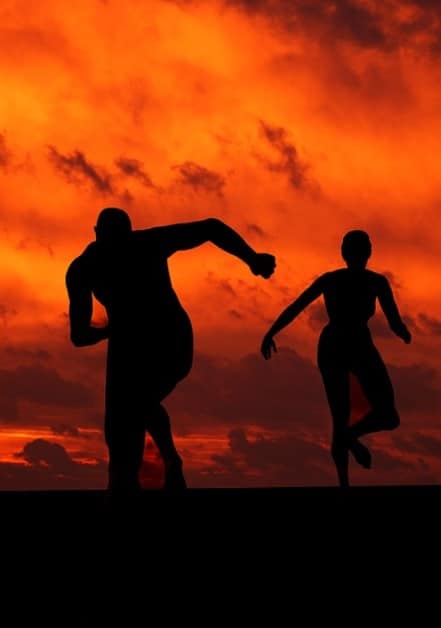 A couple running together during a sunset.