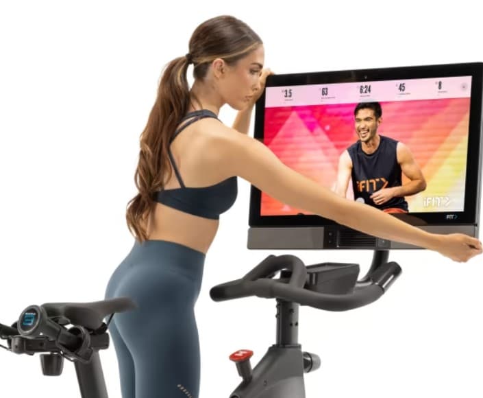 NordicTrack Commercial S27i Studio Cycle - with a female model setting up the screen
