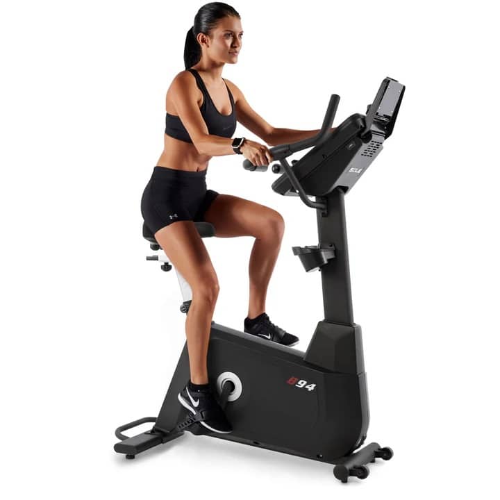 Sole B94 Upright Exercise Bike - with a female model cycling 