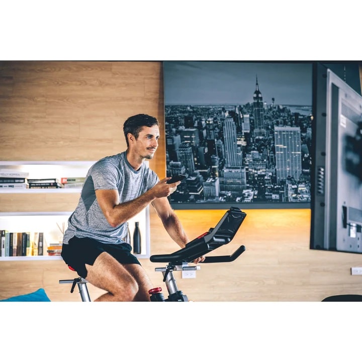 Sole SB 900 Exercise Bike - with a male model setting up phone to tv
