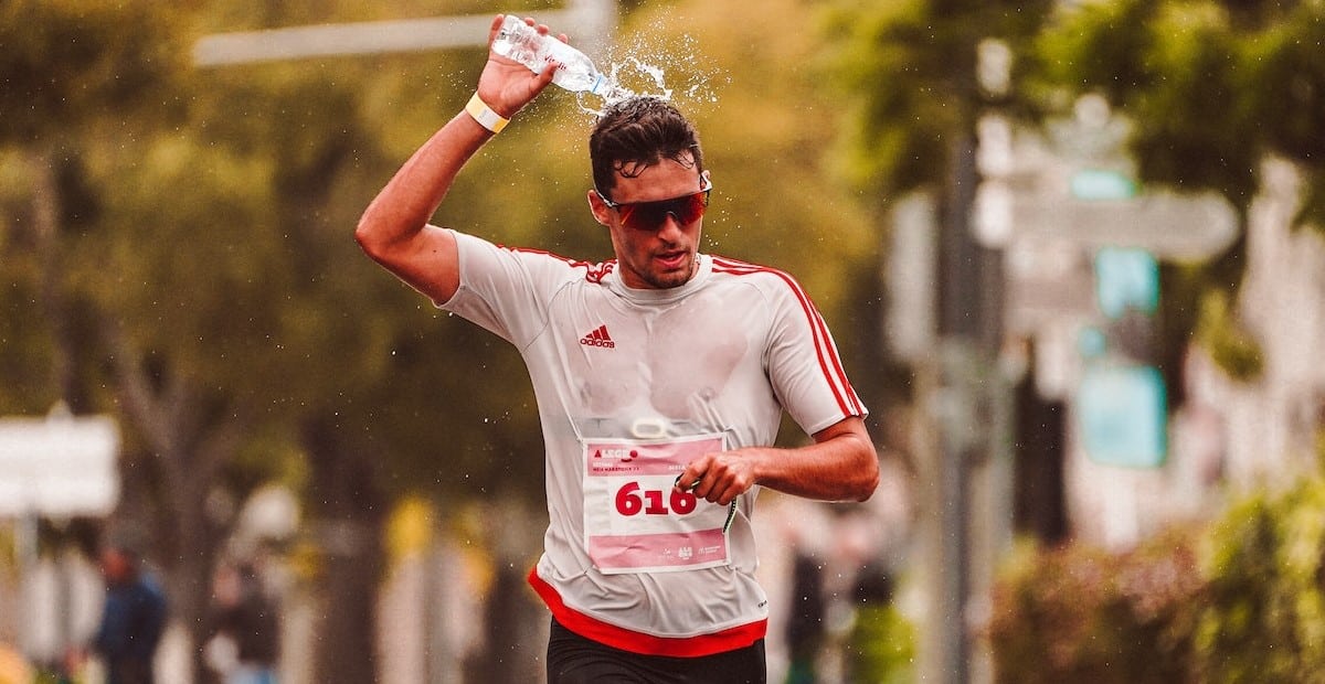 A man pouring water on himself while running. 