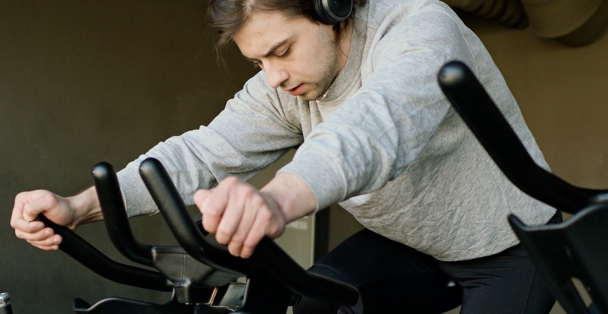 A man exercising on a bike wearing a headset 