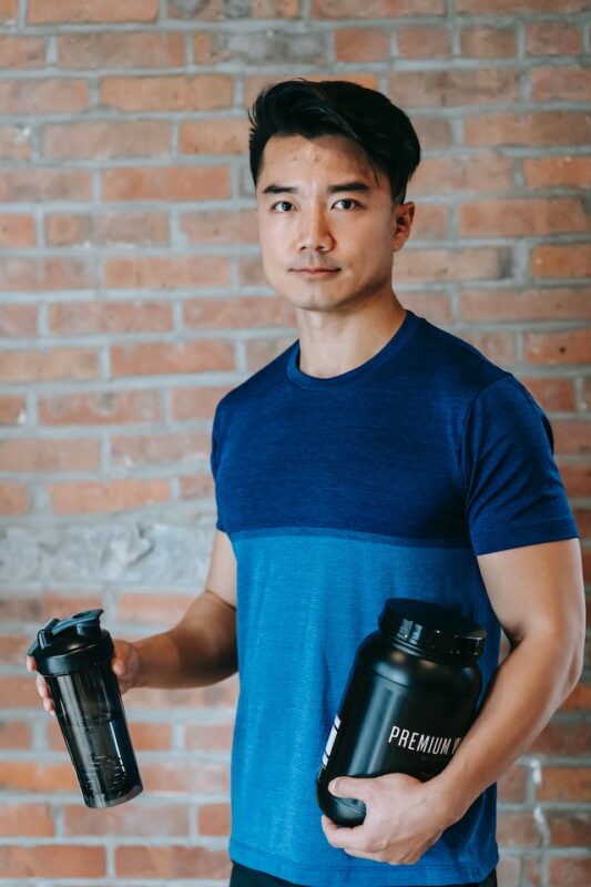 sportsman standing with protein jar and water bottle