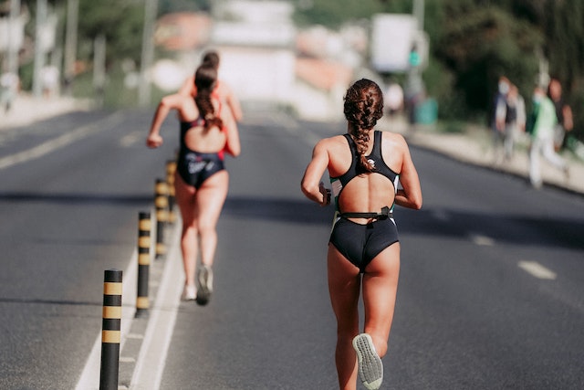 sportswomen running on asphalt road in daytime