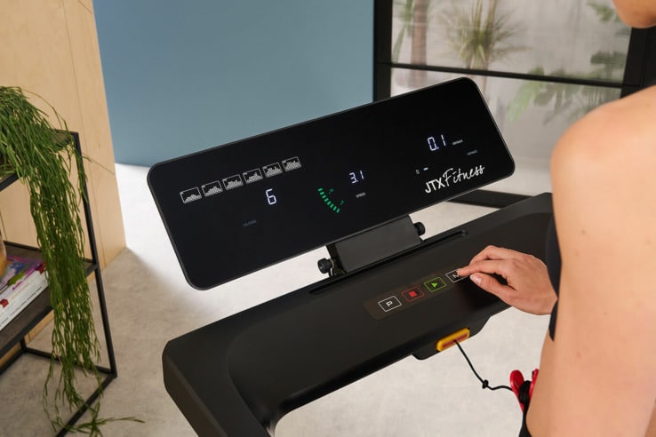 JTX Slim-line Flat Fold-away Treadmill with a model using the control buttons 