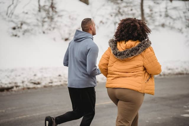 A man and woman running in winter park
